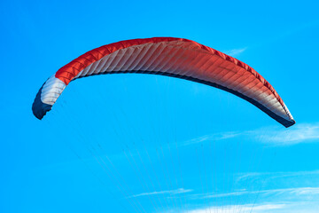 Red-white-blue paraglider filled with the wind close-up. A multi-colored wing of a paraglider against a clear sky. Paraglider in the sunlight against the blue sky.