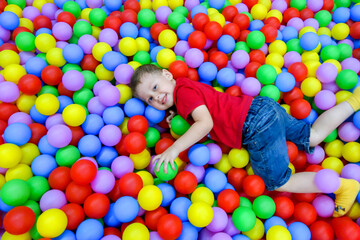 Fototapeta na wymiar the boy lies in the pool with colored balls