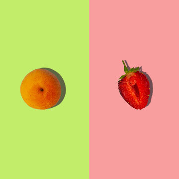 Apricot and strawberry square composition with hard shadows flat lay on pastel green and pink background. Creative layout of fresh summer fruits. Food fun concept. Trendy pop art design.