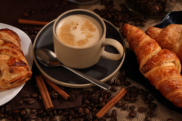 A Cup of coffee, cinnamon, and a couple of croissants on burlap