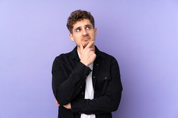 Caucasian man isolated on purple background having doubts