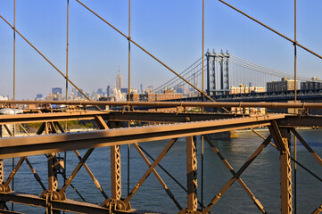 Vue sur le pont de manhattan à travers la structure d'acier du pont de brooklyn et gratte-ciel à l'horizon dans un soleil matinal.
