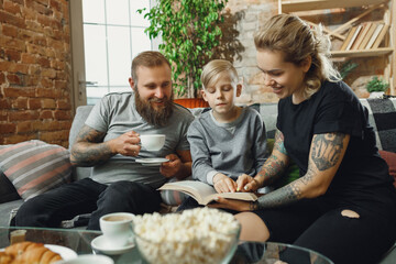 Happy family at home spending time together. Having fun, look cheerful and lovely. Mother, father and son reading book during remote school studying. Parents helping. Childhood, domestic life concept.