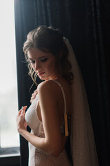Fototapeta premium Beautiful bride in white lace lingerie, with bare shoulder sitting in a hotel room. Happy wedding morning.