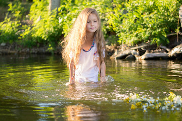 little girl with a wreath in a white dress in the water. Holiday Ivana bathed
