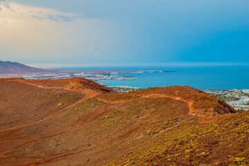 Fototapeta na wymiar panoramic view of Volcano Montana Roja de Playa Blanca, Lanzarote, Spain. One of the most popular volcano in Canary Islands and the total view of the village in the south with white houses. 