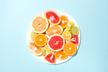 Plate with mix of citrus fruits on blue background.