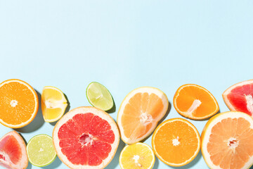 Border made of mix of citrus fruits on blue background.