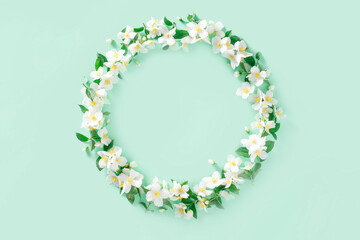 Flower composition. Wreath of white spring jasmine flowers on a pastel green background. Flat lay, top view, copy space, mockup