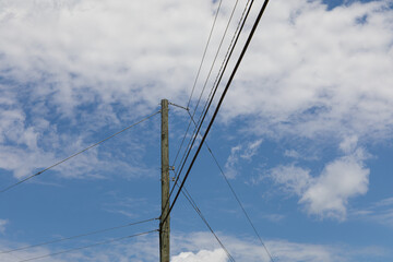 Tall wooden power pole with electrical wires running in three directions, against a beautiful blue...