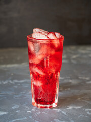 Fruit lemonade with cherry and ice cubes in a tall glass