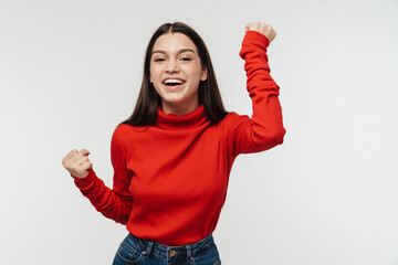 Photo of delighted young woman making winner gesture and laughing