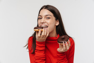 Photo of cheerful brunette woman smiling and eating chocolate donuts