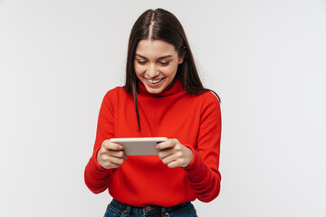 Photo of cheerful woman smiling while playing video game on cellphone