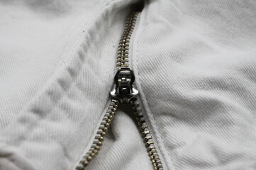 Macro close up of isolated white casual denim jeans pants with metal teeth zipper (focus on slider)