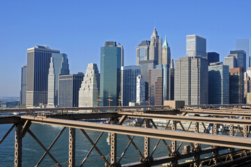 Fototapeta premium Vue sur le quartier des affaires de manhattan depuis le pont de brooklyn, la structure de poutres en acier contrastant avec les gratte-ciel en verre à l'horizon.