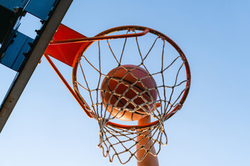 Street basketball slam dunk competition. Close up of ball falling into the hoop. Urban youth game. Concept of success, scoring points and winning © CrispyMedia