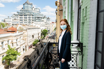 Side view of woman in medical mask looking at camera on terrace