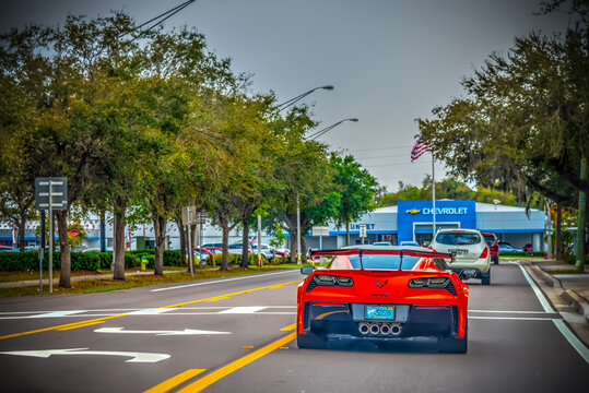 Red Corvette seen from behind with Chevrolet dealership on the background