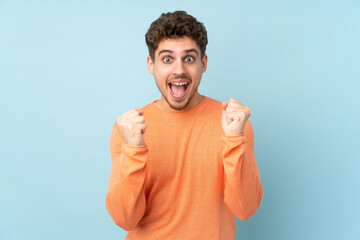 Caucasian man isolated on blue background celebrating a victory in winner position