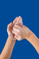 Fototapeta premium Closeup of person cleaning hands with soap, on blue background