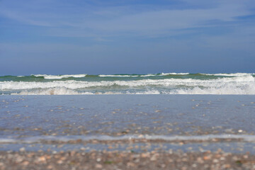 Wet sand, a sea with dark-colored waves and a deep blue sky