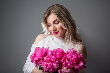 Beauty portrait of a lovely young woman posing with peonies flower