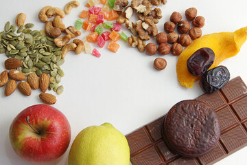 Proper nutrition without sweets. Replacing sweets with nuts and dried fruits, mangoes, dates, green pumpkin seeds, almonds, hazelnuts, walnuts or chocolate and flour on a white background