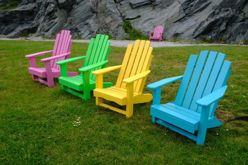Multicoloured wooden chairs on grass