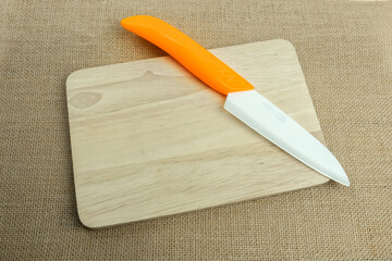 new and modern ceramic knife on wooden chopping board.