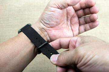 Adjusting watch strap to tighten.