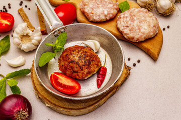 Raw and fried cutlets, fresh vegetables, spices, olive oil. Vintage pan, picnic or barbecue cooking concept