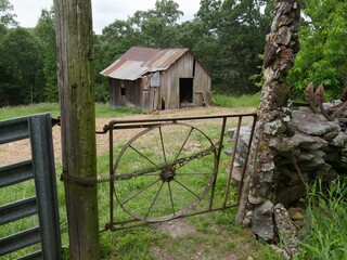 Dilapidated barnhouse in a farm with an improvised gate from the wheel of  a wagon