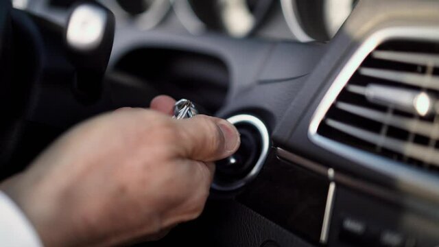 Men's hand turns key in ignition car start
