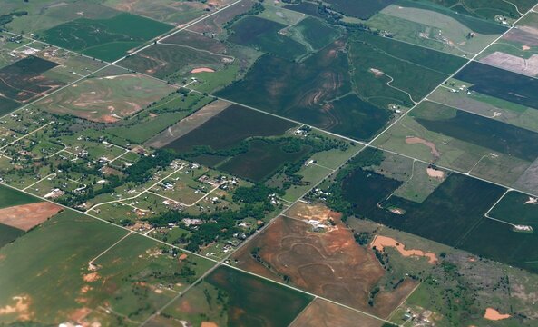 Wide aerial view of green sprawling farmlands enroute to Dallas seen from an airplane window - Powered by Adobe