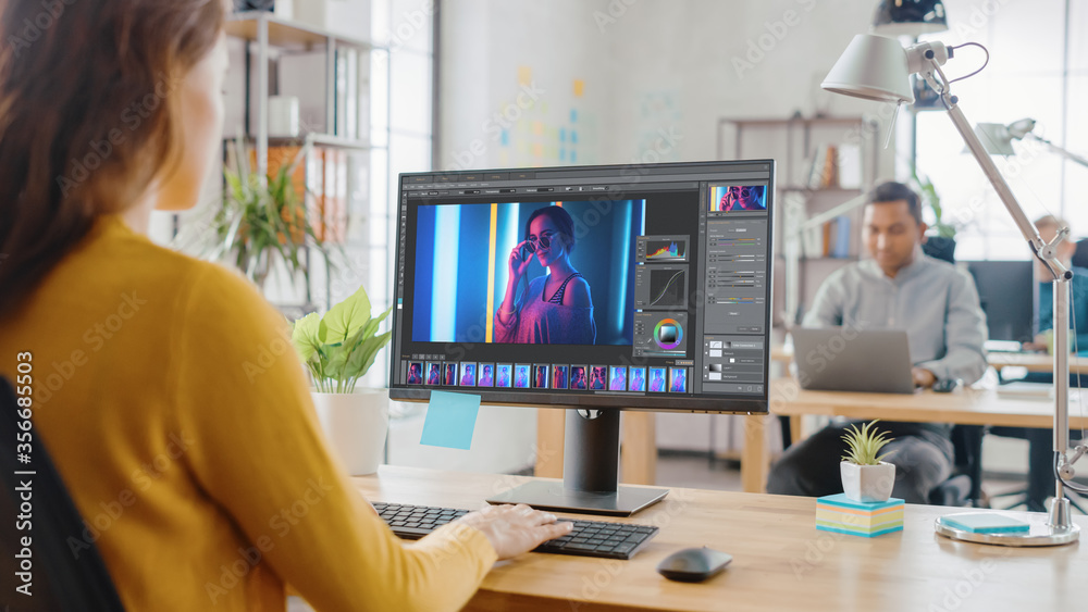 Poster over the shoulder: creative young woman digital editor works in photo editing software on her person