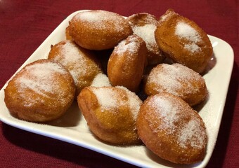 Wide shot of a plate full of fried bread with white sugar on top