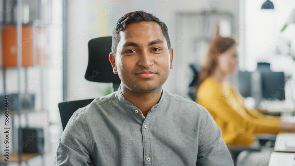 Aufkleber portrait of handsome professional indian man working at his desk, using personal computer and smilin