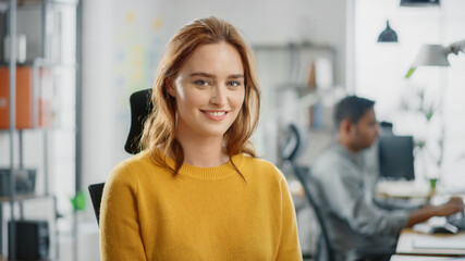 Portrait of Beautiful Young Woman with Red Hair Wearing Yellow Sweater Smiling at Camera...