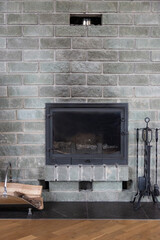 gray brick wall fireplace with traces of black soot. cast-iron fireplace accessories and firewood...