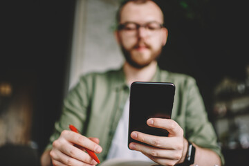 Bearded hipster guy holding mobile phone in hands and chatting