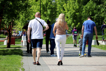 Crowd of people walking in a summer park. Concept of fashion in hot weather, leisure in a city after coronavirus quarantine