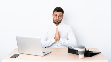 Young businessman in a workplace keeps palm together. Person asks for something