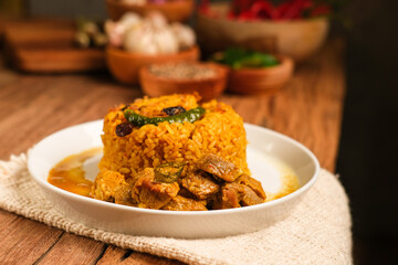Indian Mutton Biryani Dish served on wooden table. Typical food from India, made from goat meat mixed with spices and basmati rice