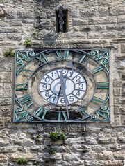 An ancient metal clock on a stone wall, Arco, Italy
