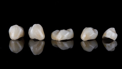 ceramic high-quality dental tabs - crowns on black glass with reflection