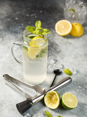 lemonade with lemon, lime and mint with ice, in a glass glass on a gray background