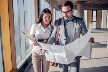 Two dedicated hardworking positive architects walking in building in construction process and...