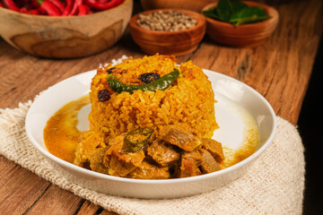 Indian Mutton Biryani Dish served on wooden table. Typical food from India, made from goat meat mixed with spices and basmati rice