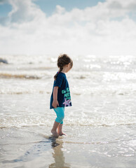 Unrecognizable little girl looking at the sea on a sunny day in a concept of looking to the future, starting over and hope after the covid-19 quarantine in Italy
